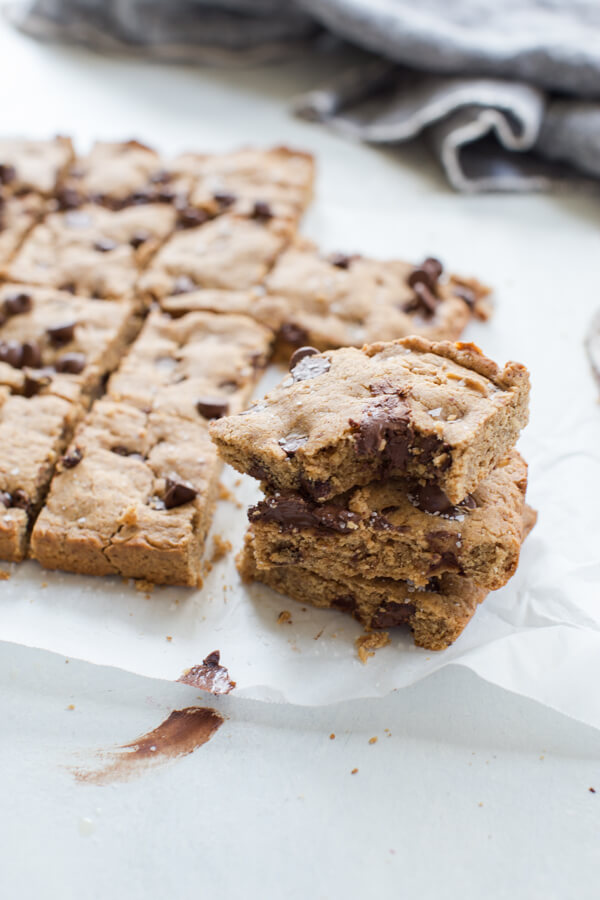 Side shot of two stacked almond butter blondies with a chewy and chocolatey center 