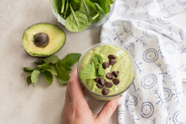 hand reaching for a glass of mint chocolate chip avocado smoothie