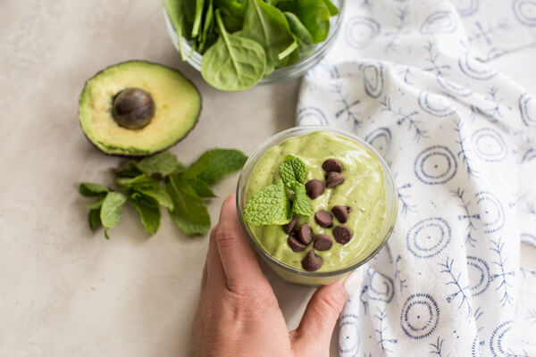 hand holding glass of mint chocolate chip avocado smoothie