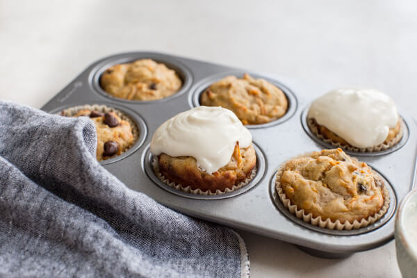 muffin tin of carrot cake muffins with chocolate chips and Greek yogurt frosting 