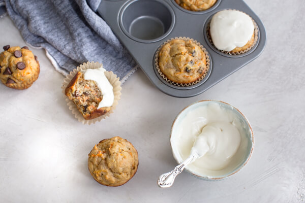 overhead shot of carrot cake muffins with bowl of Greek yogurt frosting