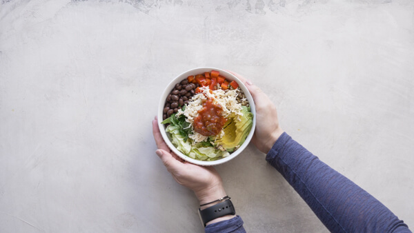 overhead shot of bowl with shredded chicken breast, black beans, diced tomatoes, shredded cheese and avocado 