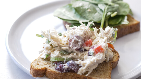 slice of bread with shredded chicken salad and fresh spinach 