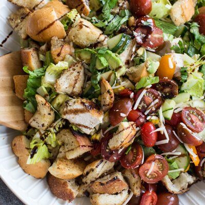 "End of Summer" Chicken Panzanella Salad recipe made with fresh tomatoes, cucumbers, chunks of toasty garlic bread, grilled corn, fresh basil, parmesan cheese. It's packed with perfectly seasoned grilled chicken for satiating protein and smothered in a thick balsamic vinegar. YUM!