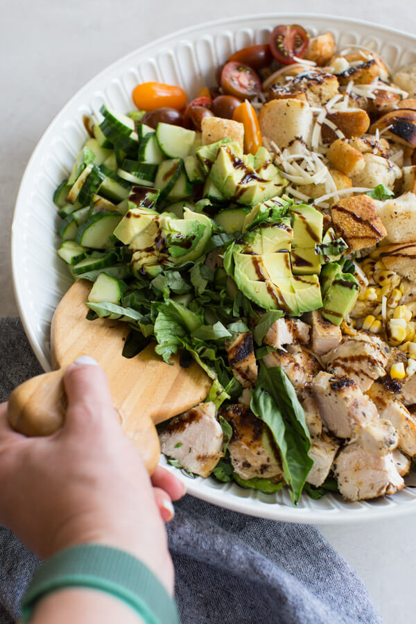 "End of Summer" Chicken Panzanella Salad recipe made with fresh tomatoes, cucumbers, chunks of toasty garlic bread, grilled corn, fresh basil, parmesan cheese. It's packed with perfectly seasoned grilled chicken for satiating protein and smothered in a thick balsamic vinegar. YUM!